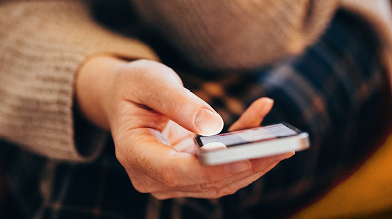 Woman’s hand holding a smartphone, viewed from the front