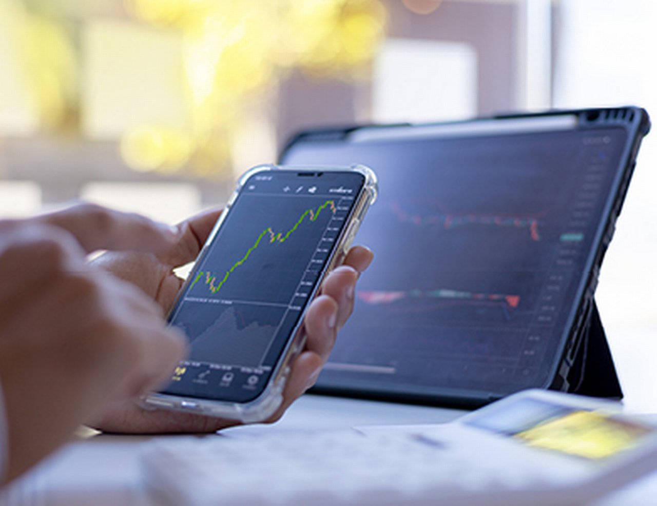 Close-up of a smartphone in a man's hand with a stock chart on the display.