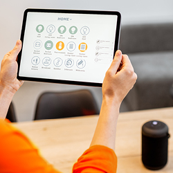 Person h&auml;lt ein Tablet mit einer Benutzeroberfl&auml;che zur Steuerung von Smart-Home-Ger&auml;ten