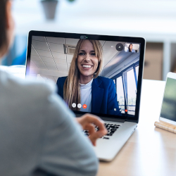 Lächelnde Frau nimmt per Laptop an einer Videokonferenz teil