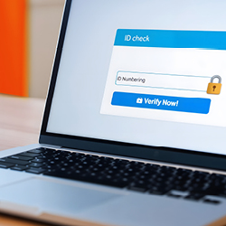 A laptop on a table displays a website with an ID verification form