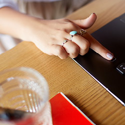 Frauenhand mit ausgestrecktem Zeigefinder nutzt den Fingerabdrucksensor zum Entsperren des Laptops