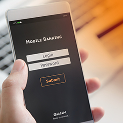 A person holds a smartphone with an open mobile banking login screen