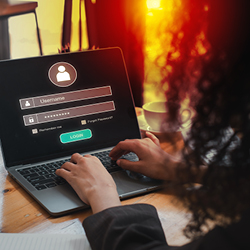 Eine Person tippt auf einem Laptop mit Login-Bildschirm ihren Benutzernamen und ihr Passwort ein