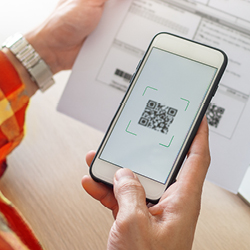 A person scans a QR code on a paper document using their smartphone